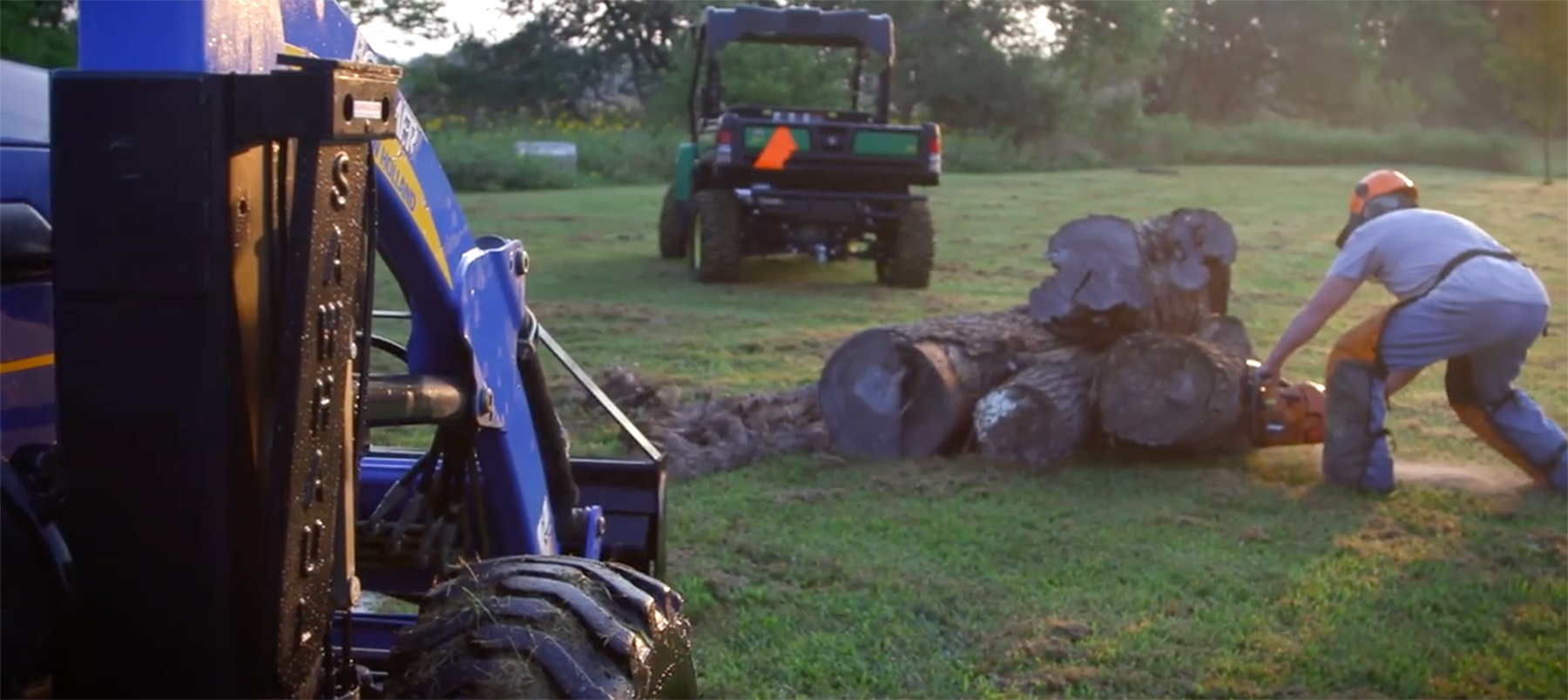 SawHaul on tractor near man cutting wood at dusk 