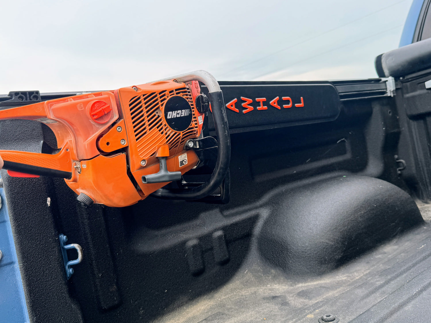 ORANGE CHAINSAW IN A SAWHAUL SNAP LOK ON A TOYOTA BED RAIL