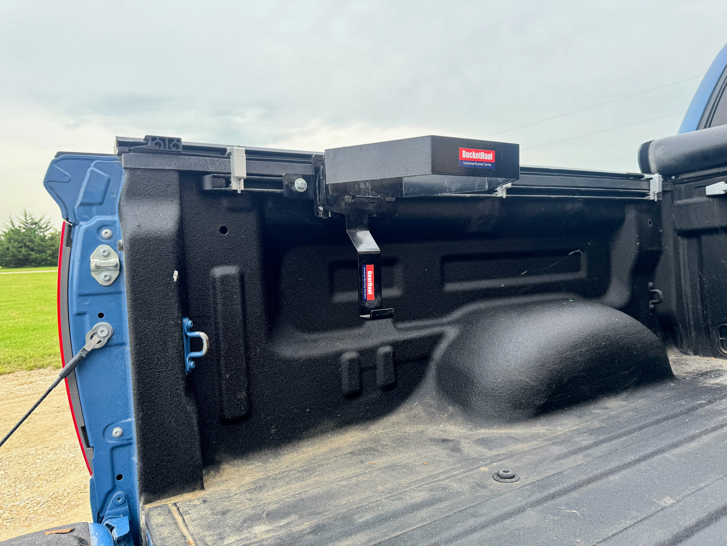 Truck bed with a buckethaul and visible branding on a grassy field background.